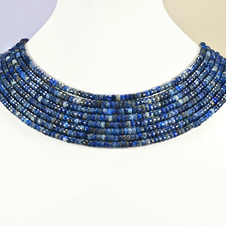 Dark blue lapis faceted heishi disc strands arranged as a layered collar on a white display bust, dark blue beads across the neck