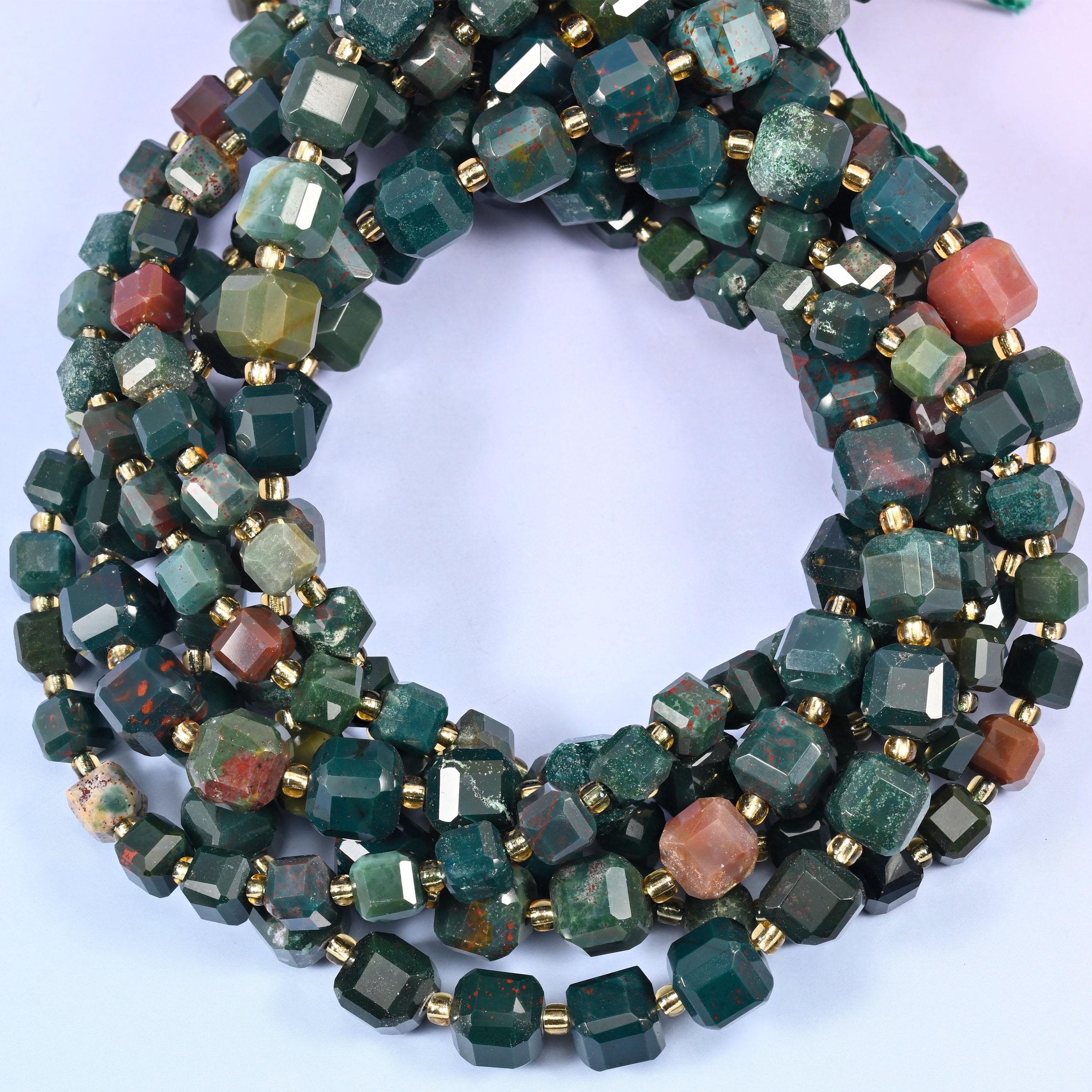 Deep forest and sea green mottled with dark grey, broken up by the occasional coral-pink or rust bead, each cube faceted on every side.