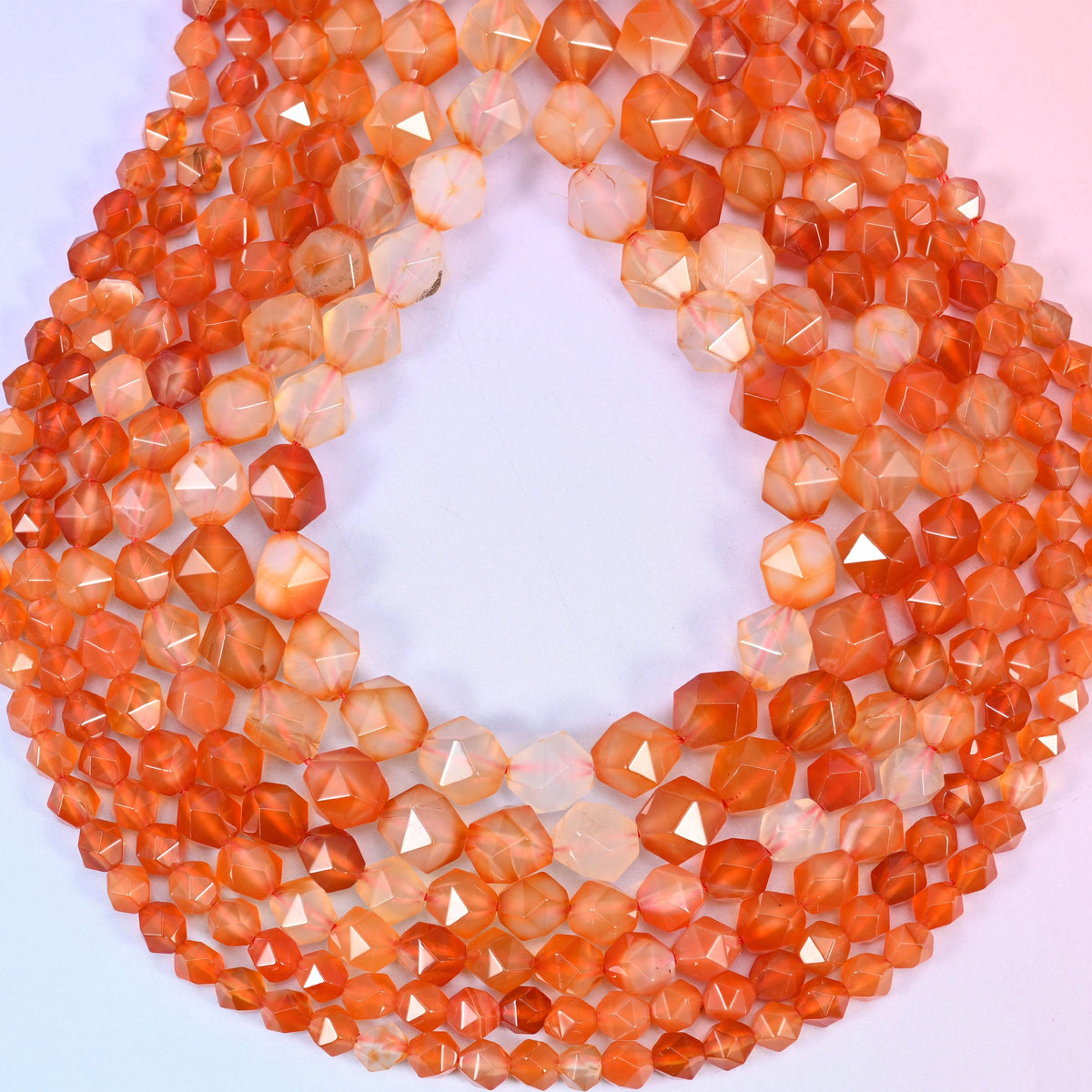 Orange Agate beads coiled into a loop, star facets throwing highlights across the warm orange stone