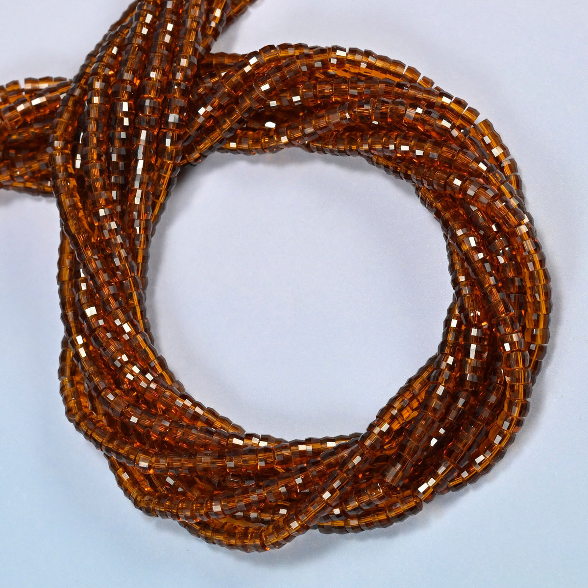 Brown glass faceted heishi disc beads coiled into overlapping loops, whole strands of amber brown glass