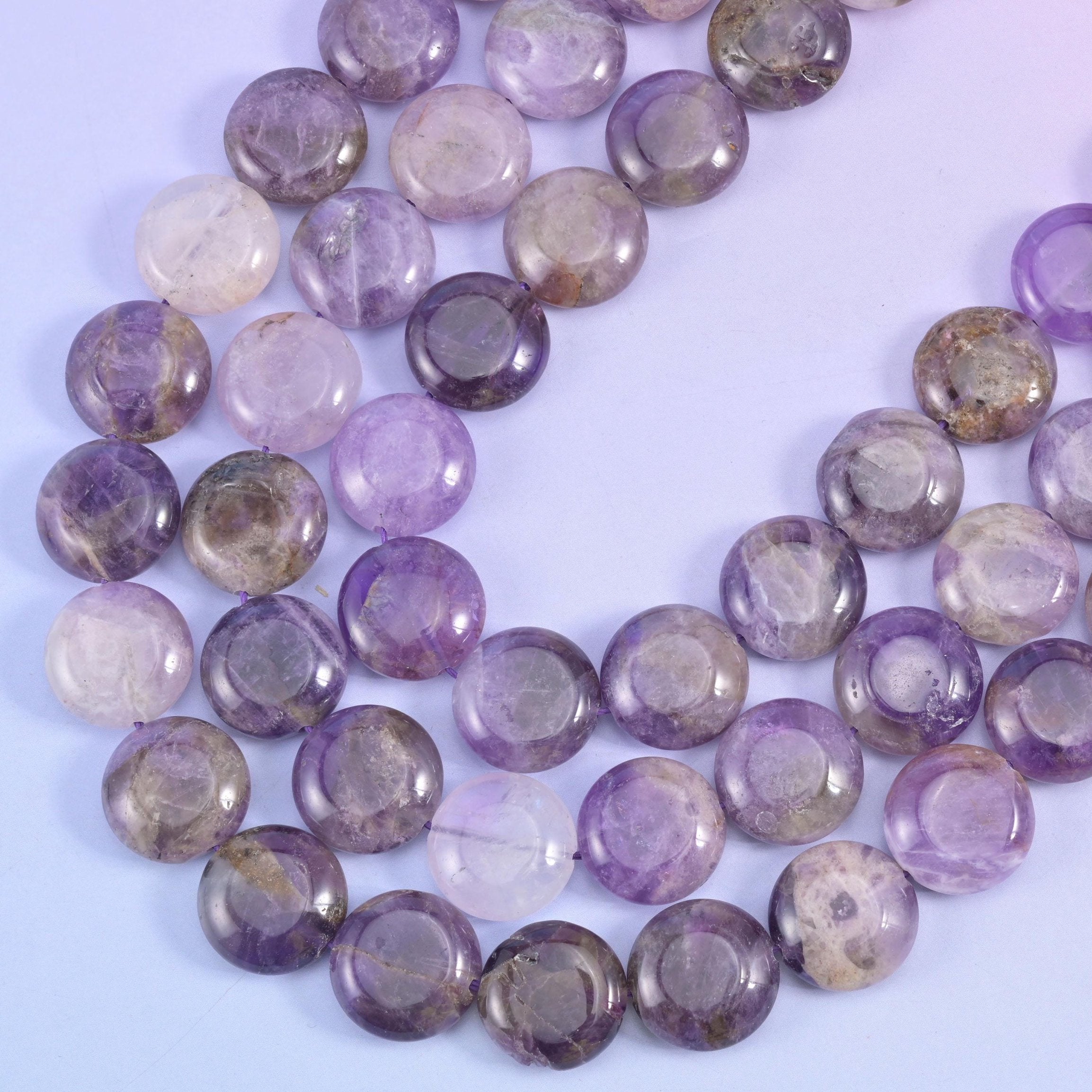 Amethyst coin strands sweeping in a curve, clear violet beside cloudy grey