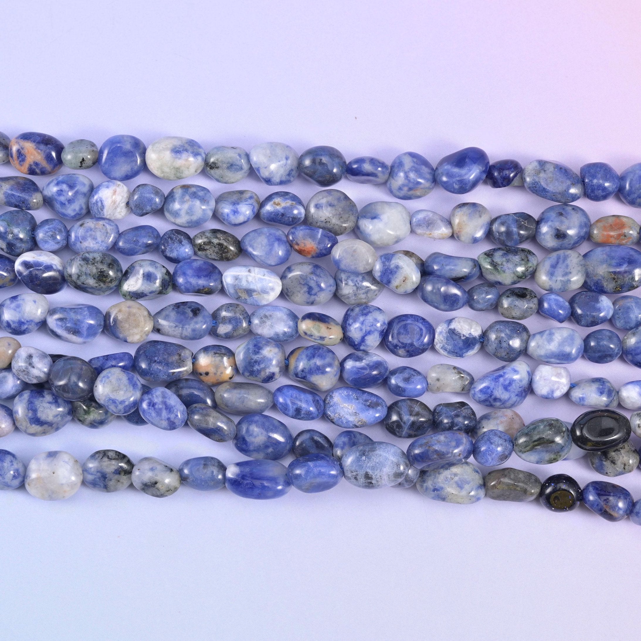 Lighter blue and grey Sodalite nuggets laid out in parallel strands