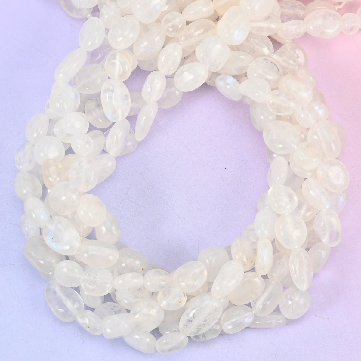 White Moonstone Pebble Nugget Beads — milky white and semi-translucent with a faint cool blue shimmer sliding under the surface, tumbled into smooth rounded nuggets that sit softly against the skin.