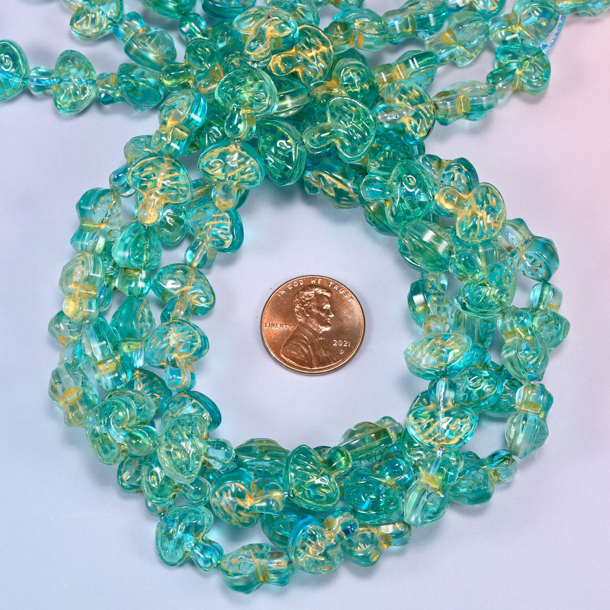 Aqua gold flat mushroom glass beads coiled into a tight spiral, the strand end trailing off the top corner.