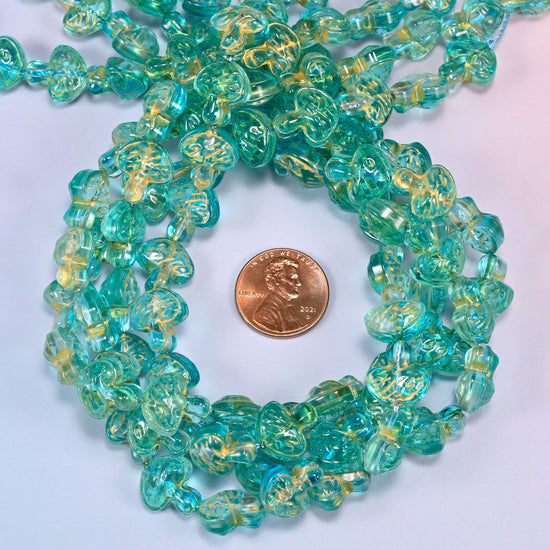 Aqua gold flat mushroom glass beads coiled into a tight spiral, the strand end trailing off the top corner.