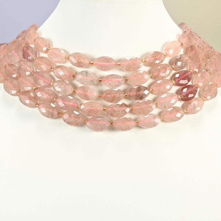 Strawberry quartz faceted flat oval strands arranged as a layered collar on a white display bust, soft pink beads across the neck