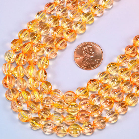 Yellow gold pumpkin glass beads, several strands laid in a wide sweeping curve across the frame.
