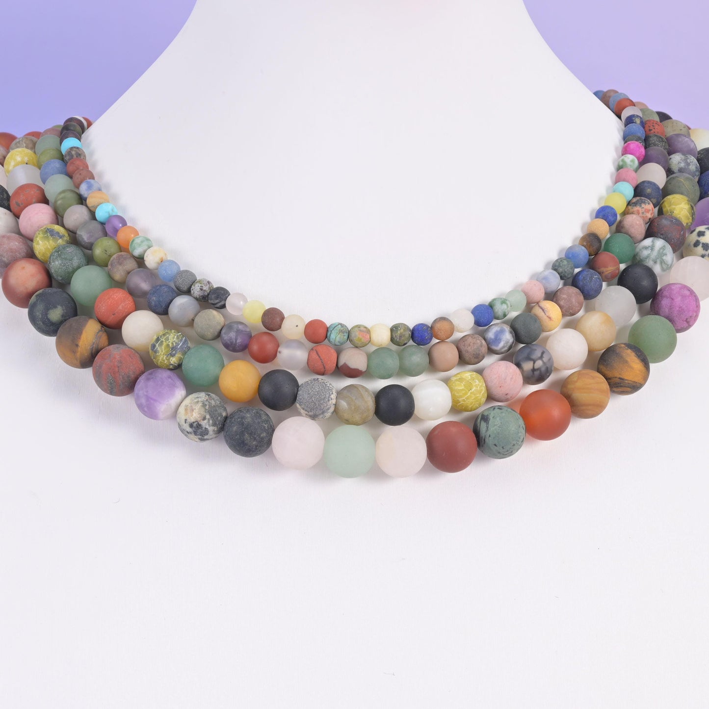 Assorted matte gemstone rounds layered on a white neck display form