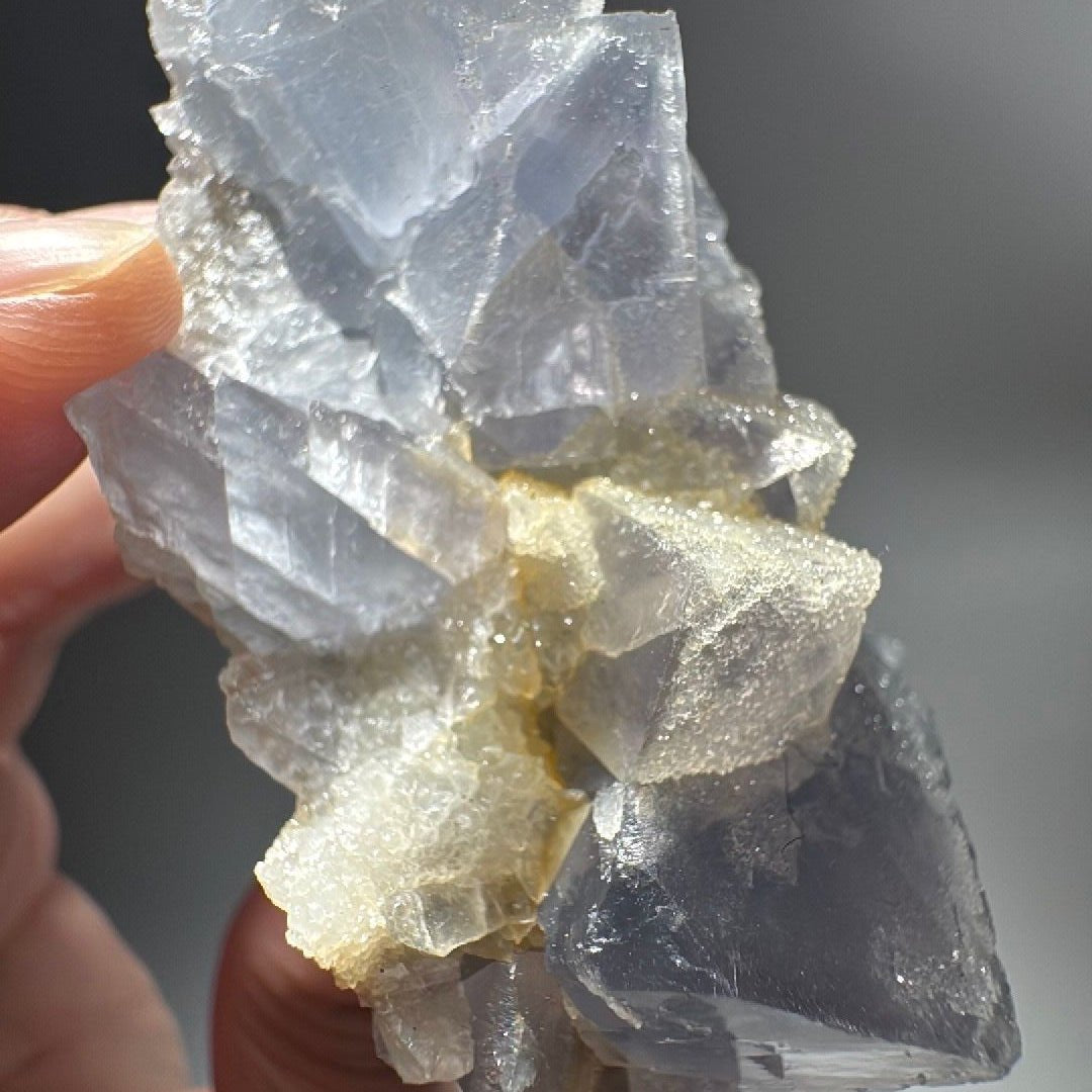 Side view of the fluorite specimen, creamy quartz crusting packed between translucent blue crystal faces