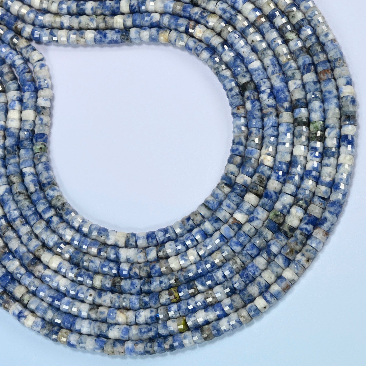 Blue spot jasper faceted heishi disc beads curved into an open loop, white and light gray beads with blue spots