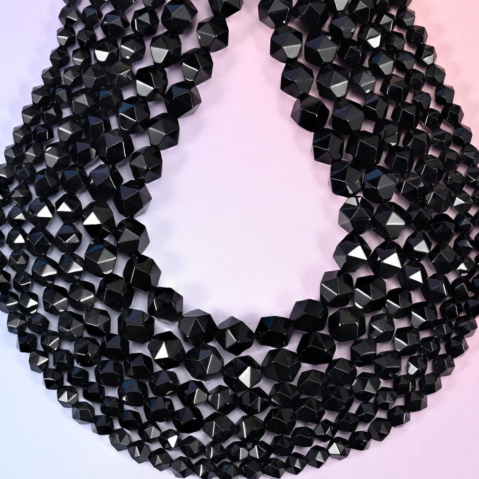 Black Onyx beads coiled into a loop, star facets throwing bright highlights across the polished black surface