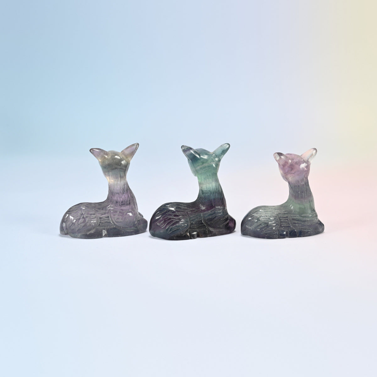 Three resting deer carvings in natural purple, green and teal fluorite