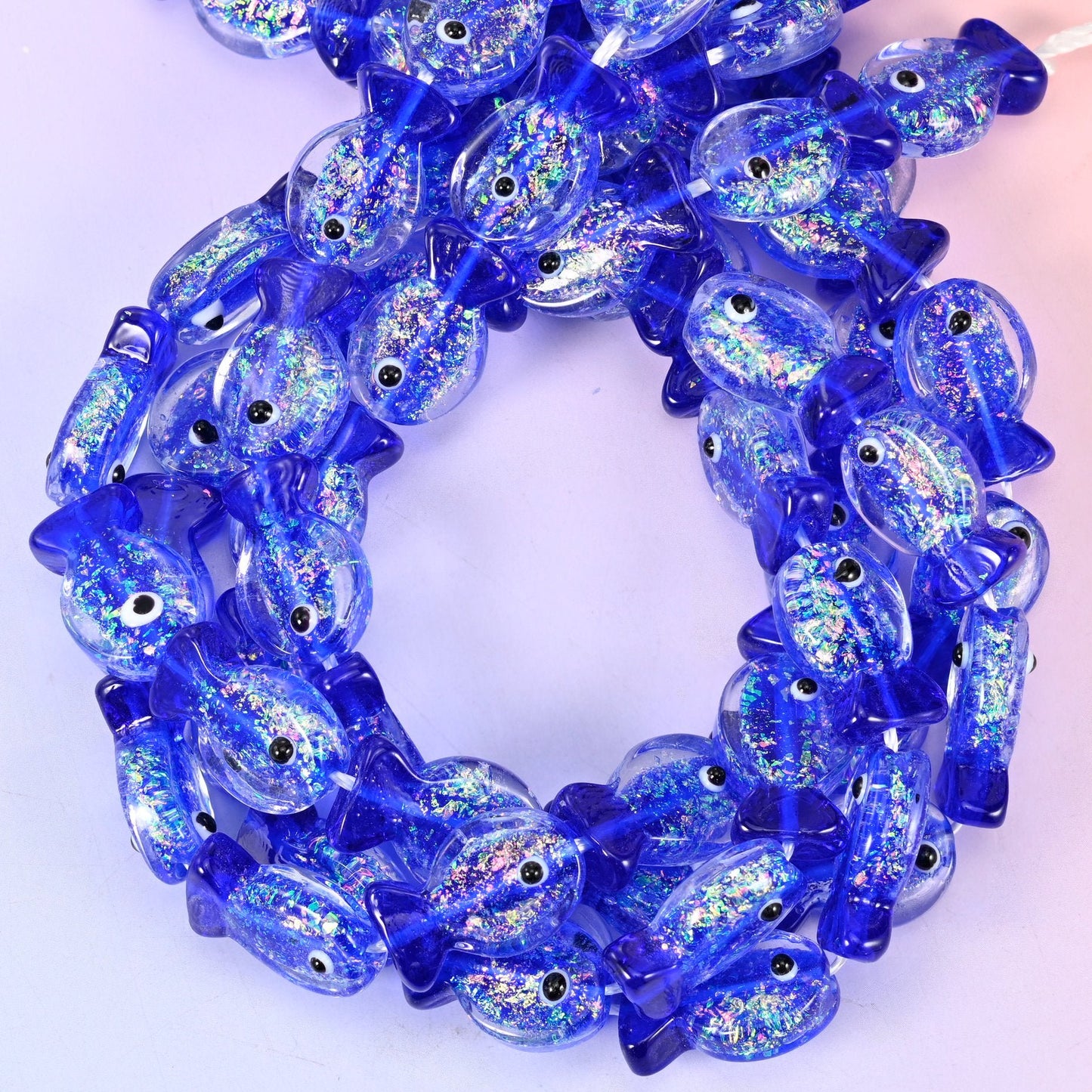 Iridescent Dark Blue Fish Glass Beads — cobalt blue glass fish with a silvery glitter core caught inside the clear belly, a moulded tail and fin, and a single black dot eye.