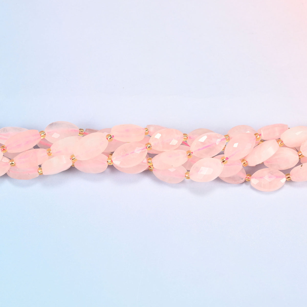 Strands of rose quartz faceted flat oval beads twisted together in a horizontal row