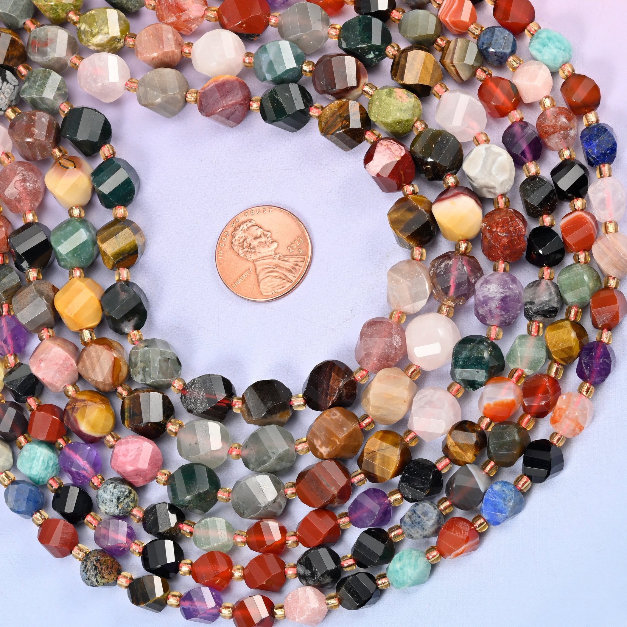 A full colour wheel of stones on one strand, each bead cut into a faceted barrel with the facets spiralling round it — violet amethyst, pale rose quartz, golden tiger's eye, jet black onyx