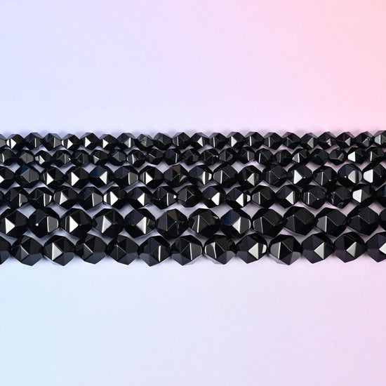 Black Onyx faceted beads in flat horizontal rows against a soft pink background, sold per 15.5 inch strand