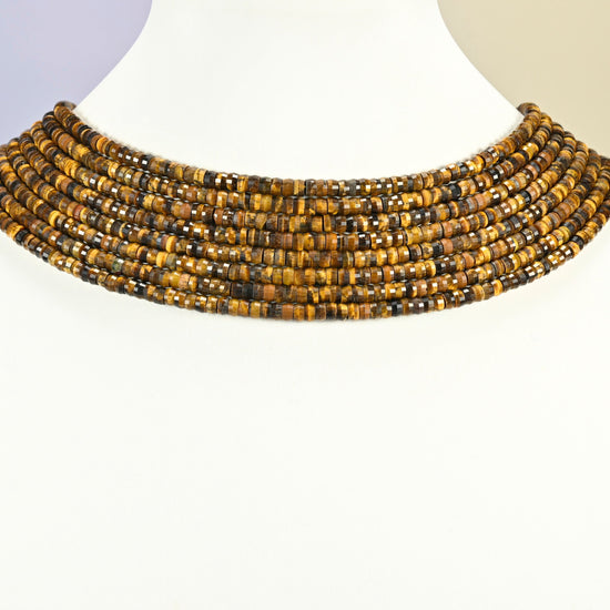 Tiger eye faceted heishi disc strands arranged as a layered collar on a white display bust, golden brown beads across the neck