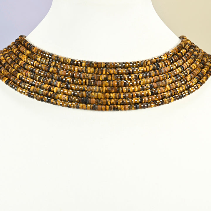 Tiger eye faceted heishi disc strands arranged as a layered collar on a white display bust, golden brown beads across the neck