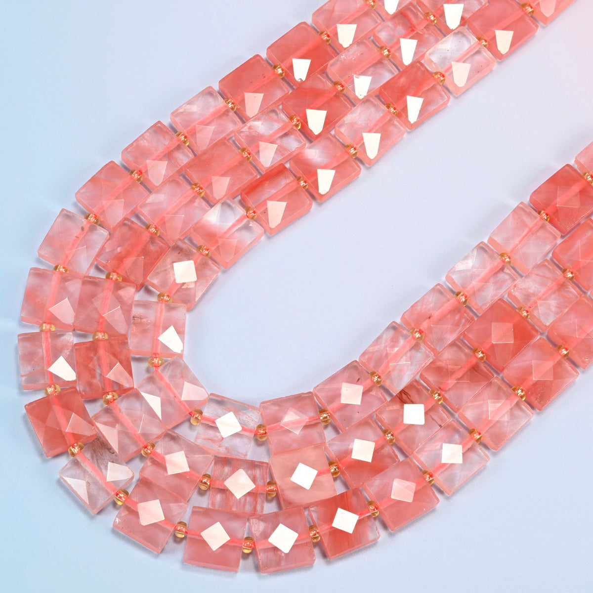 Melon quartz faceted flat square beads in several strands curved into a wide U, translucent pink glass with coral streaks