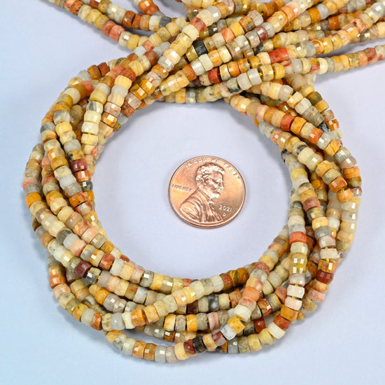 Crazy agate faceted heishi disc beads 2x4mm coiled in a loop around a US penny for scale, close-up of the faceted disc shape