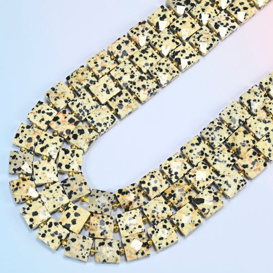 Dalmatian jasper faceted flat square beads in several strands curved into a wide U, cream with black spots