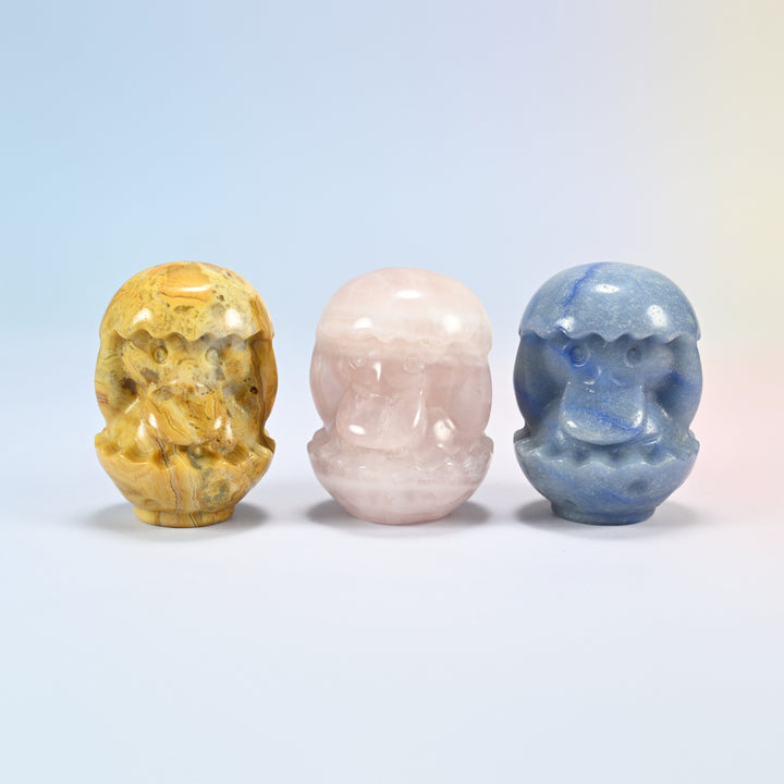 Three 2 inch duck egg crystal carvings in natural crazy agate, rose quartz and blue aventurine, each a duckling hatching from its shell