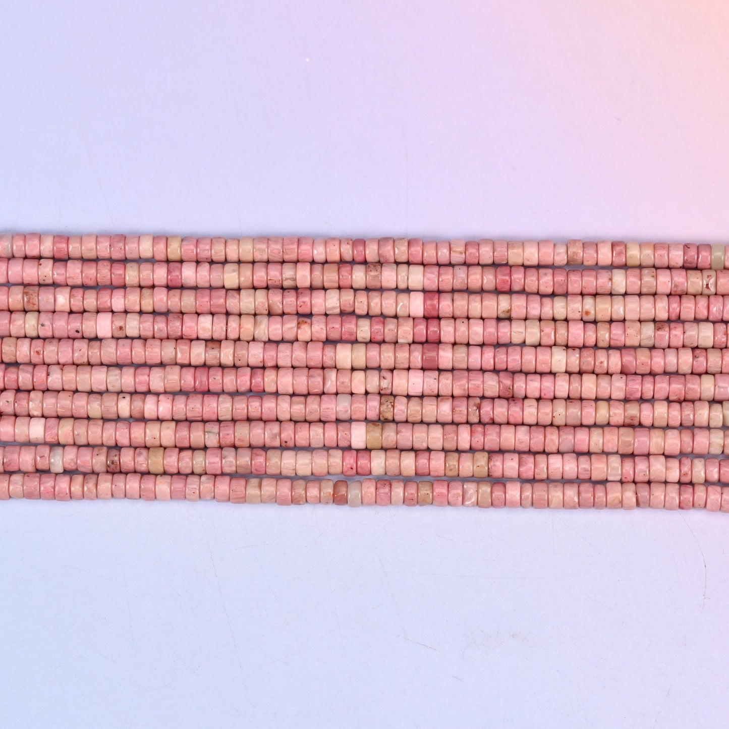 Pink Rhodonite heishi discs with a smooth polished finish.
