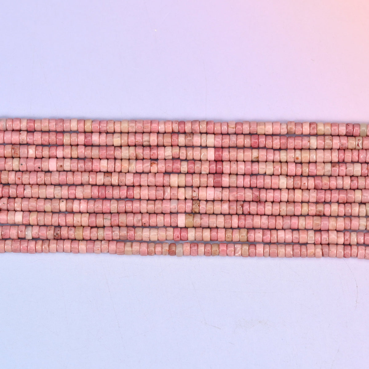 Pink Rhodonite heishi discs with a smooth polished finish.