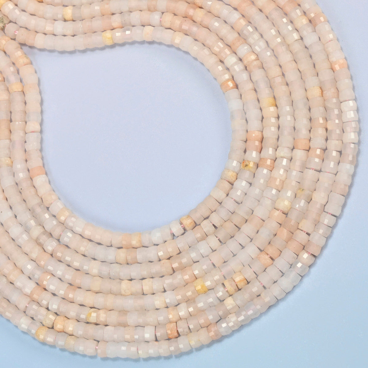 Pink aventurine faceted heishi disc beads curved into an open loop, light peach pink and light beige beads