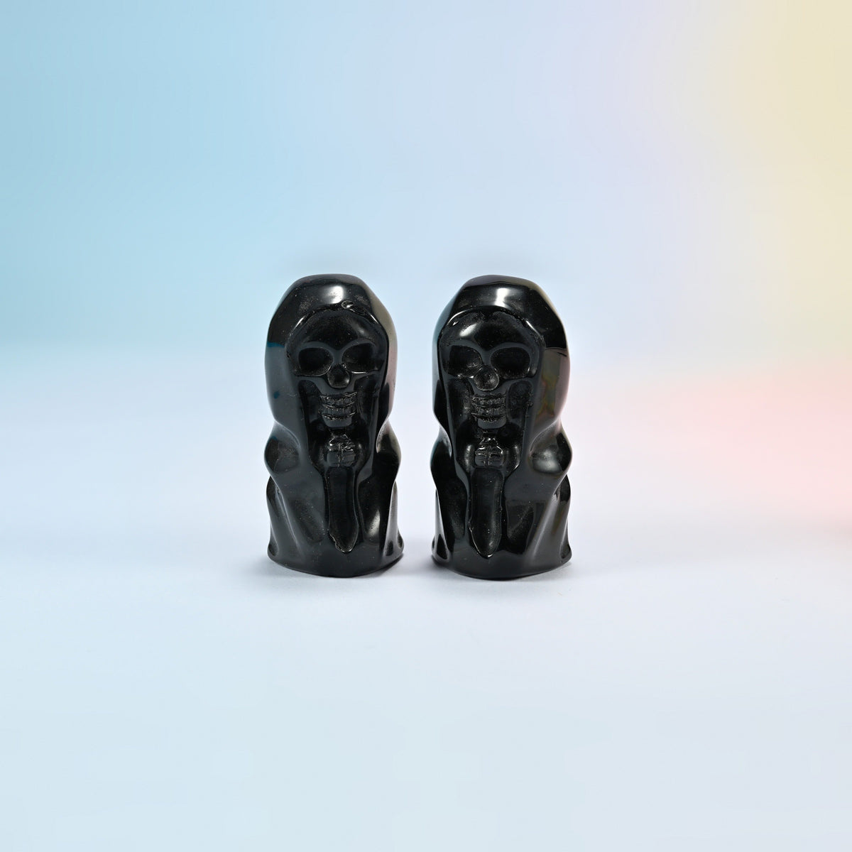 Two natural black obsidian hooded skull carvings with a glossy black polish