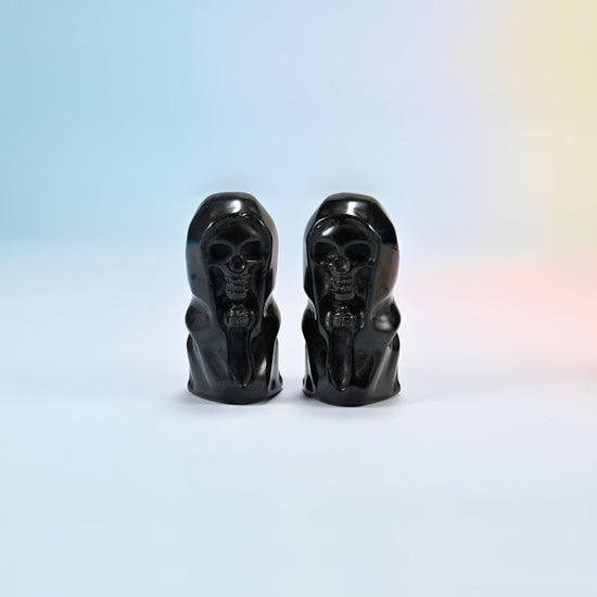 Two natural black obsidian hooded skull carvings with a glossy black polish