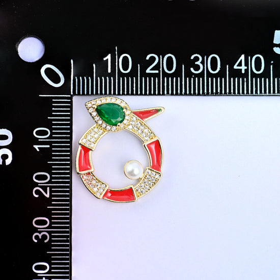 Round snake charm upright on a millimetre ruler, the red enamel ring and pearl set at the zero mark to show the width across the medallion.