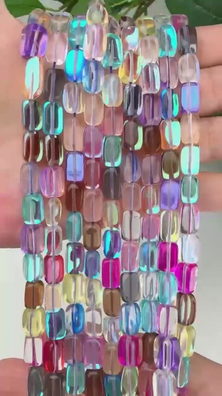 Rainbow mystic aura rectangle glass beads shown close up, the tube beads in clear, teal, amber, magenta and lilac stacked row on row.