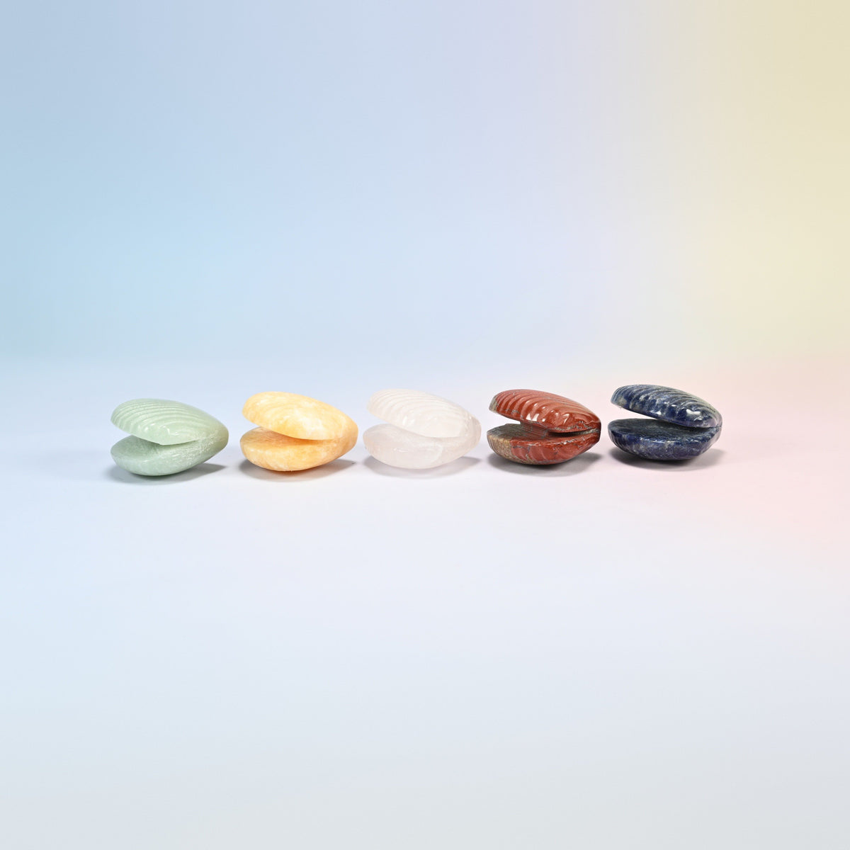 Five 1.5 inch clam shell crystal carvings in a row, natural green aventurine, yellow jade, rose quartz, red jasper and sodalite