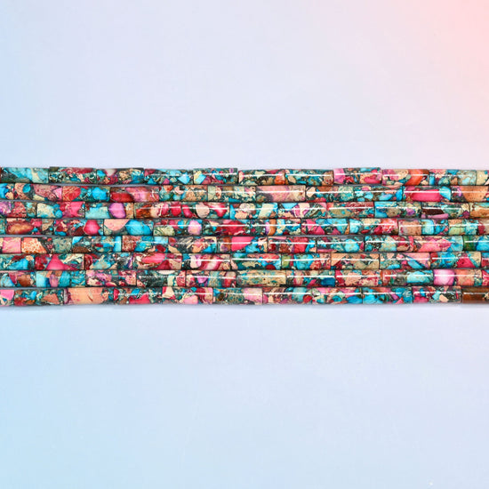 Several strands of dyed sea sediment jasper tube beads 13x4mm laid in straight rows, turquoise and pink tubes side by side