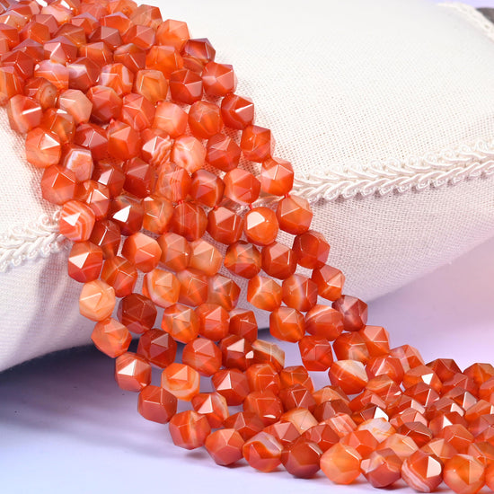 Dyed Red Stripe Agate diamond star cut beads, strands laid over white fabric, burnt orange and brick red banded with creamy white