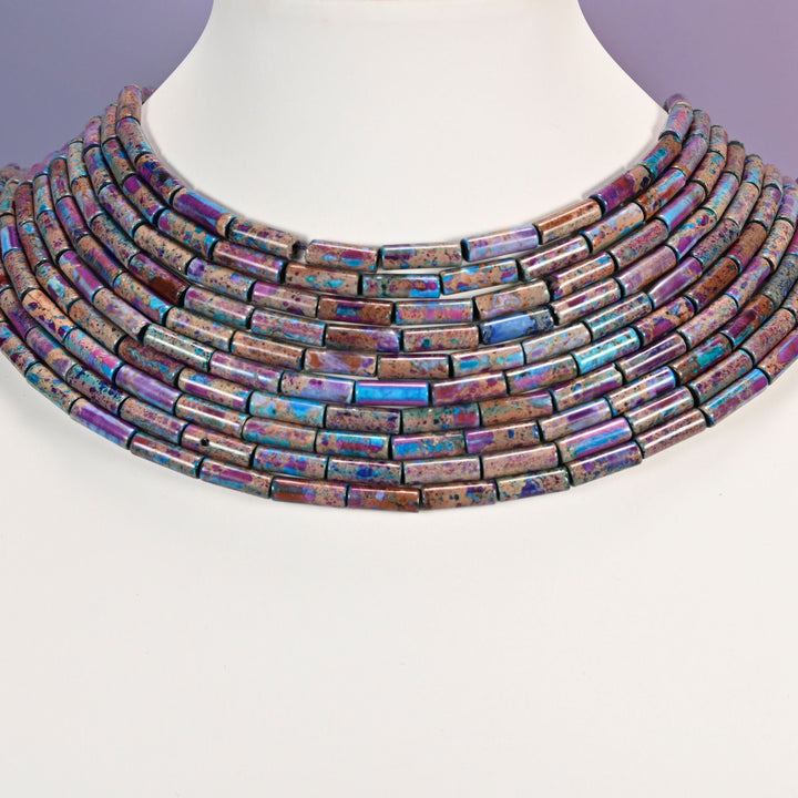 Multi-strand purple and turquoise jasper tube bead necklace laid flat on a mannequin neck form against a lavender background.