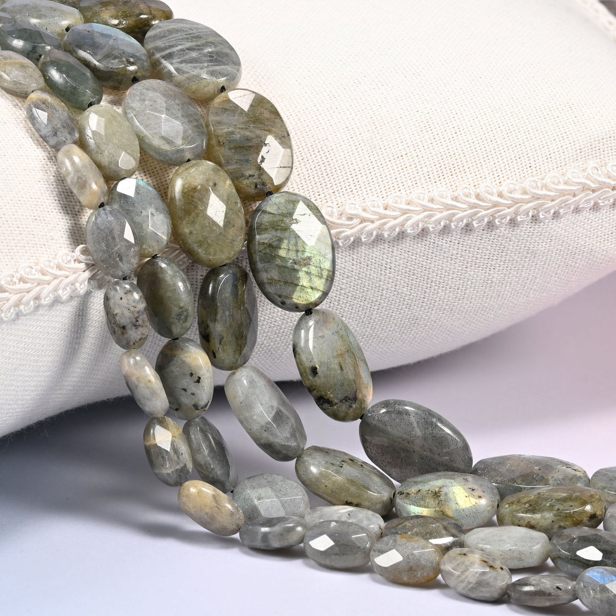 Gray Labradorite faceted oval beads draped in a soft curve, flat ovals in gray with green and gold tones