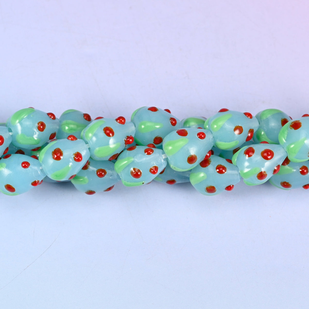 Man-made glass strawberry beads in light blue, red and green