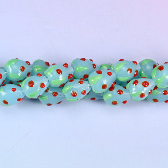Man-made glass strawberry beads in light blue, red and green