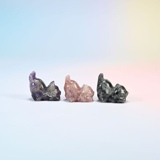 Side view of natural amethyst, strawberry quartz and black labradorite yoga cat carvings with front paws stretched out