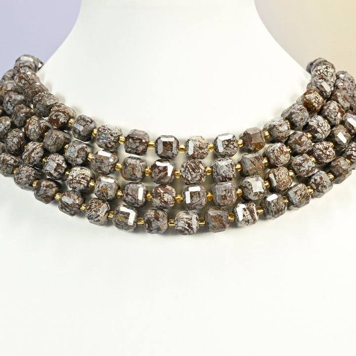 Brown snowflake obsidian faceted cube strands layered as a collar on a white display bust, gray cubes speckled with brown