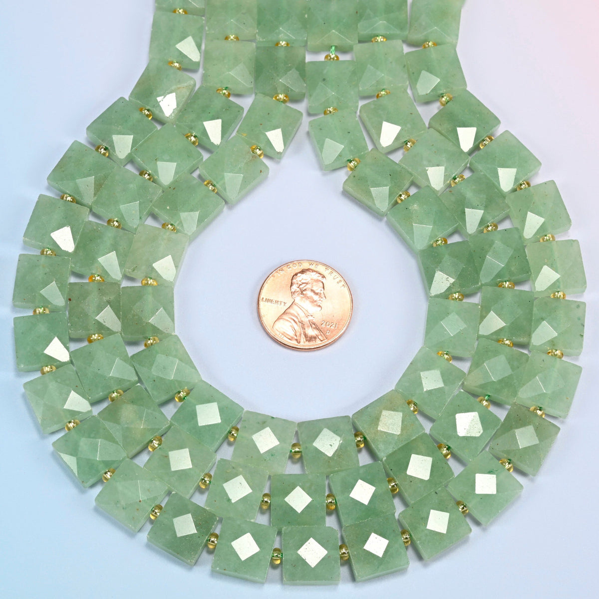 Natural green aventurine faceted flat square strands formed into a teardrop loop around a US penny for scale