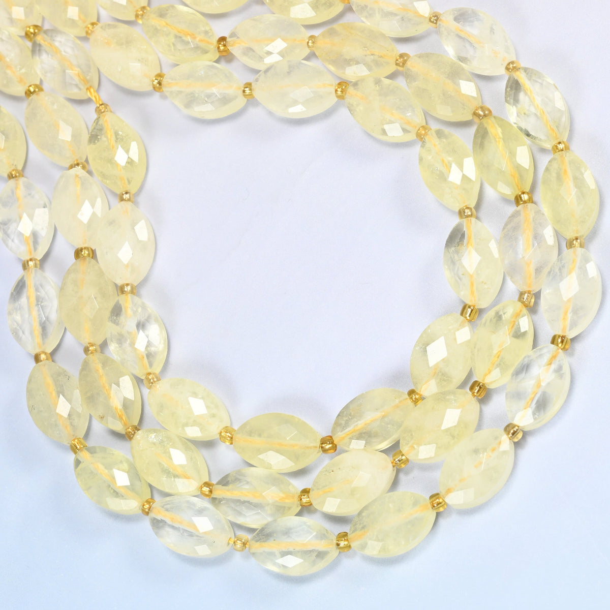 Citrine faceted flat oval beads curved into an open loop, light lemon yellow translucent beads