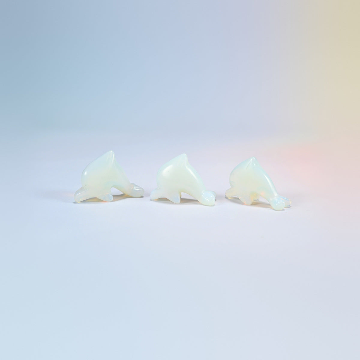 Three opalite dolphin crystal carvings, 1.5 inch, glowing milky white man-made glass