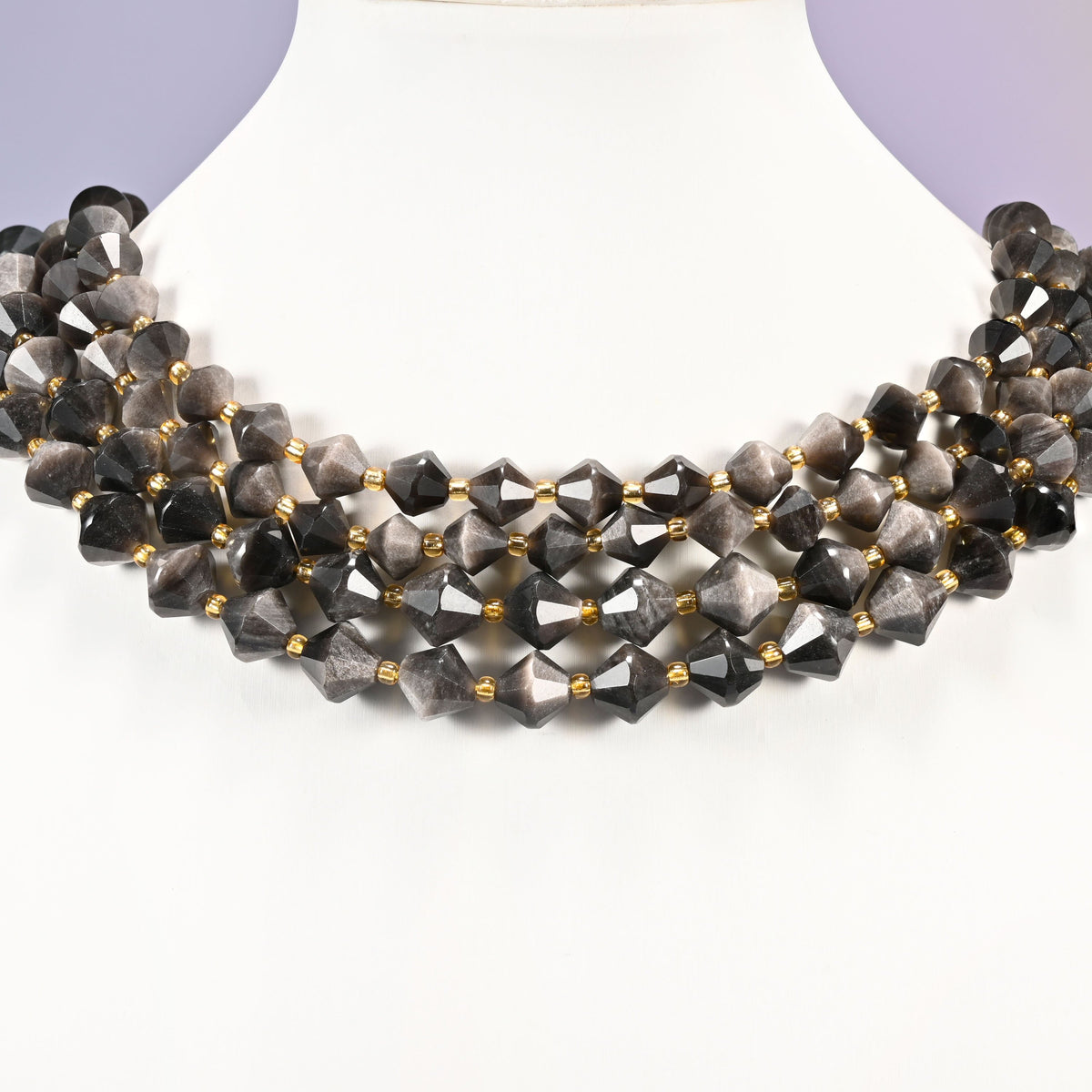 Silver obsidian bicone beads curved into a collar, the silver shimmer lifting on the beads angled into the light.
