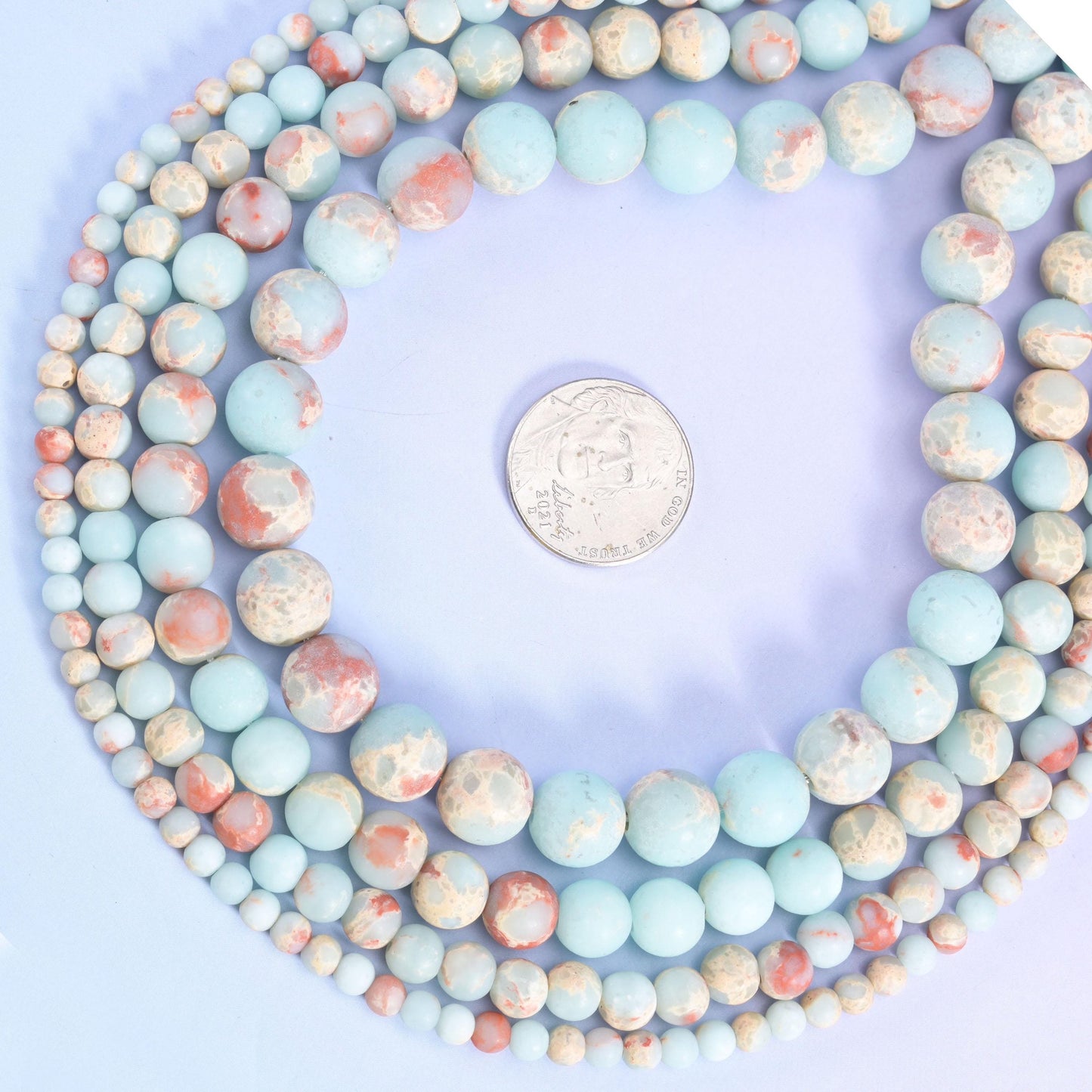Powder blue rounds marbled with cream, sand and warm terracotta veining — the pale blue and rust sitting side by side on the same bead like a desert sky. Matte finished, soft and dusty to look at.