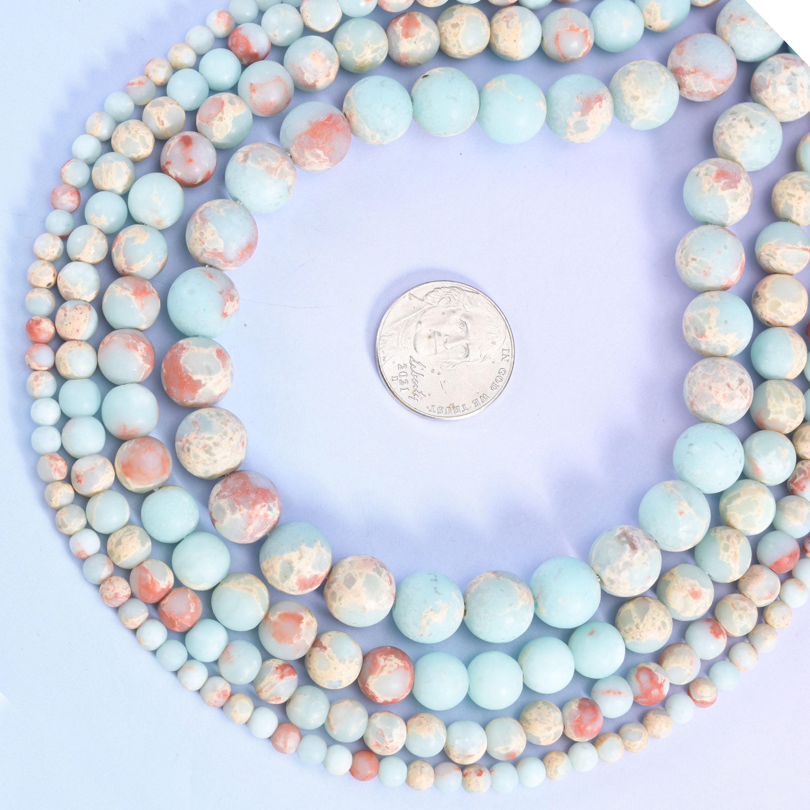 Powder blue rounds marbled with cream, sand and warm terracotta veining — the pale blue and rust sitting side by side on the same bead like a desert sky. Matte finished, soft and dusty to look at.