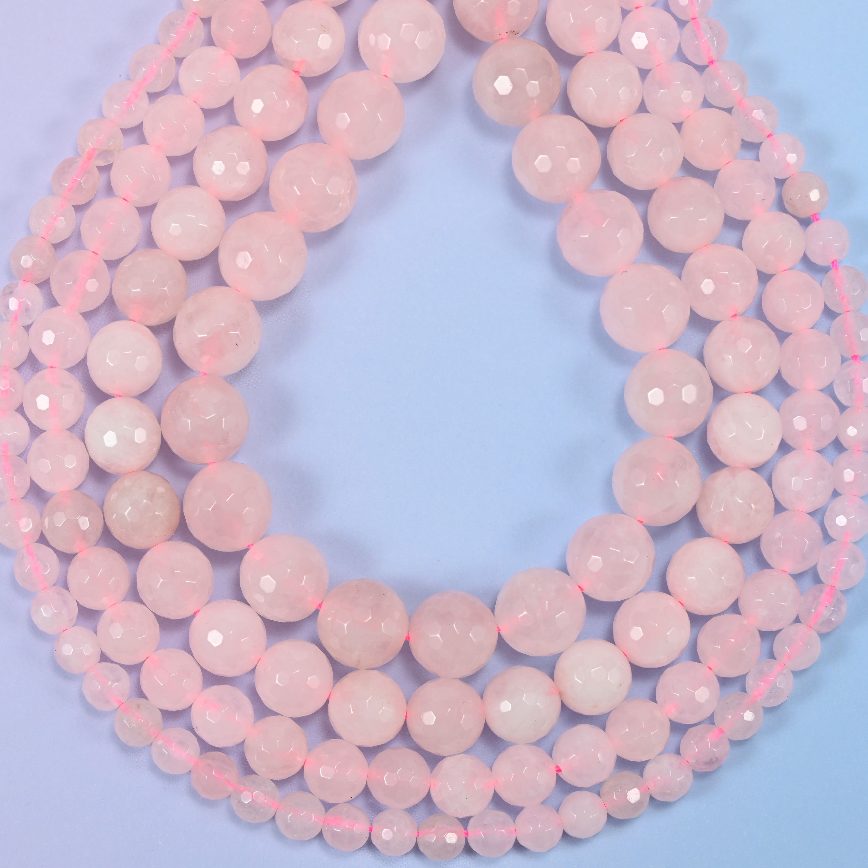 Pink rose quartz faceted round beads photographed at an angle to show natural luster.