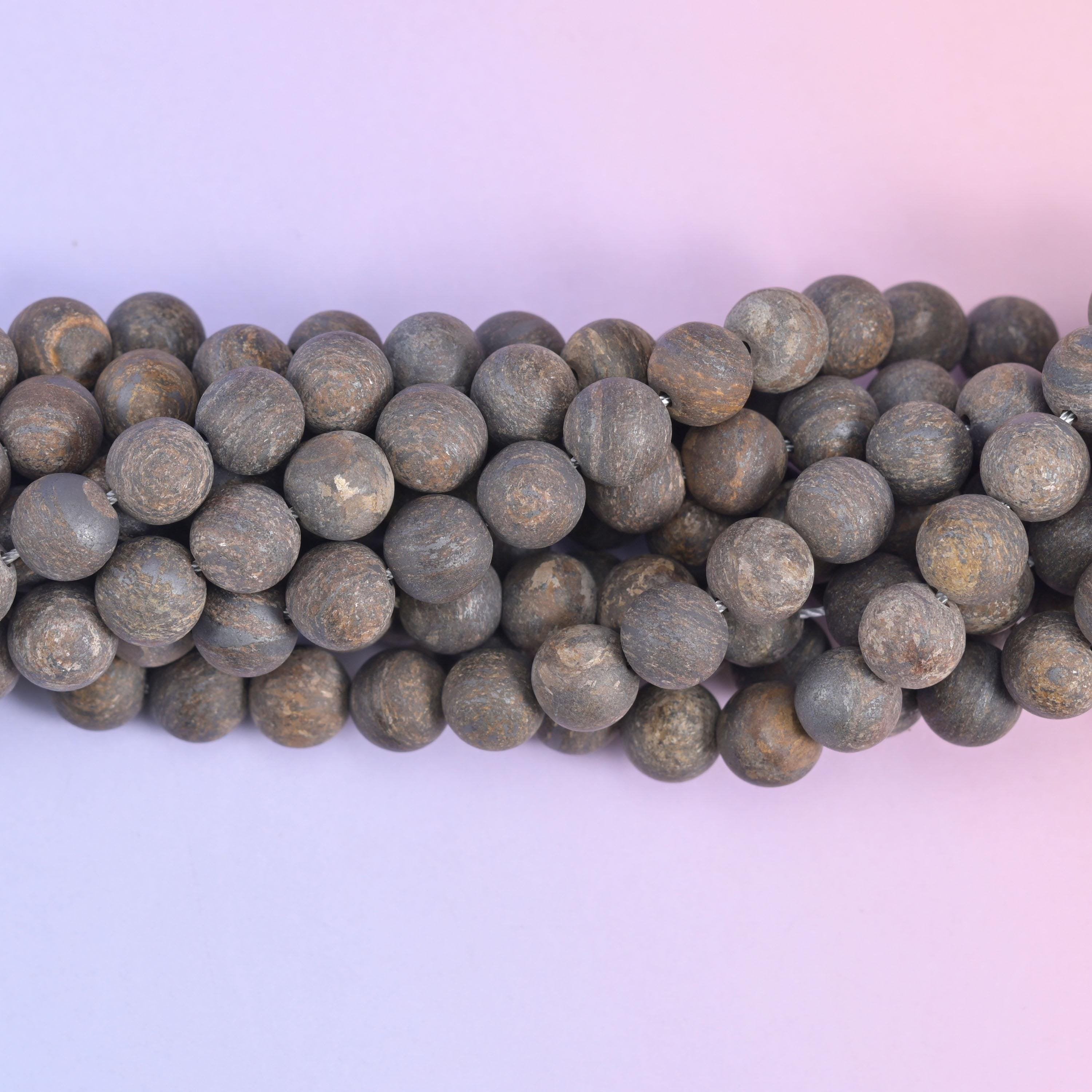 Macro view of the largest matte rounds, greyish brown surface flecked with warm bronze streaks